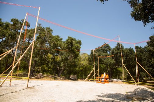 Story poles mark the proposed building surrounded by existing oak trees 